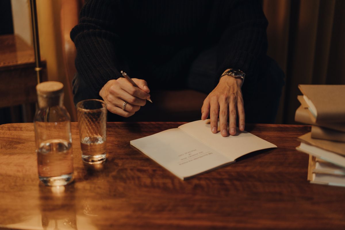 Hands typing on a keyboard with an open notebook
